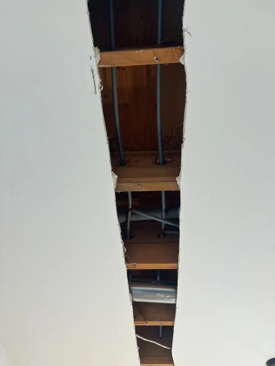 Grey Poly-B water lines in a ceiling opening before a repipe in Hollyburn, West Vancouver