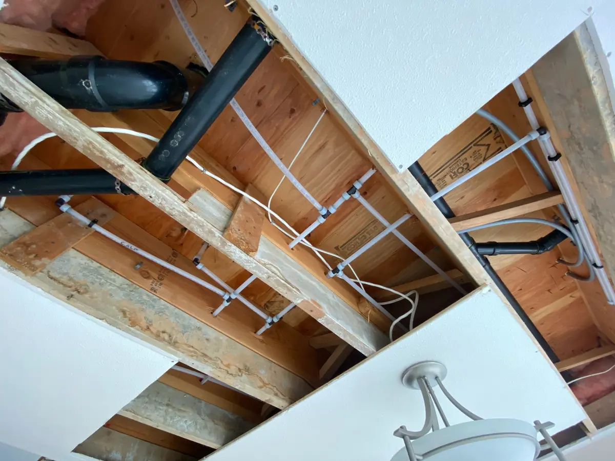 Close view of replacement water-line branches and fittings in a ceiling opening, Upper Lonsdale, North Vancouver